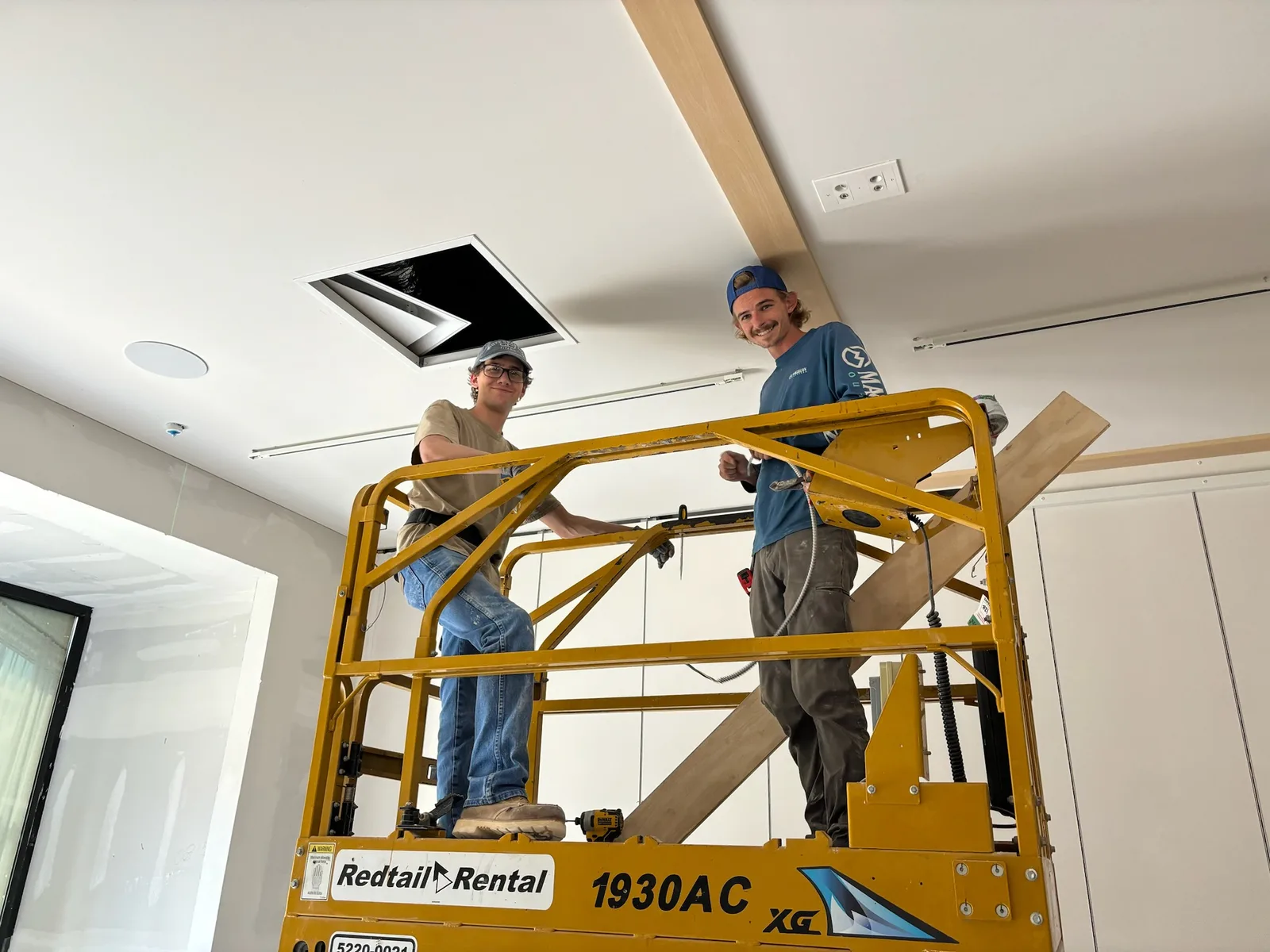 Orthodox Electric electricians installing ceiling lighting from a scissor lift